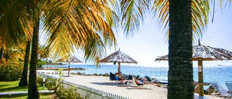 Aan het strand, wit zand, ligstoelen aan het strand, parasols