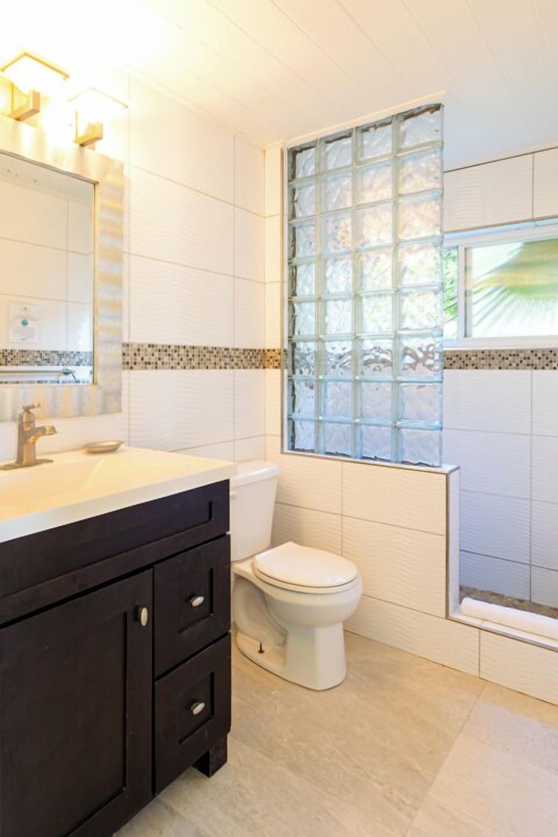 A bathroom with a toilet, a sink with a mirror, and a window with a view.