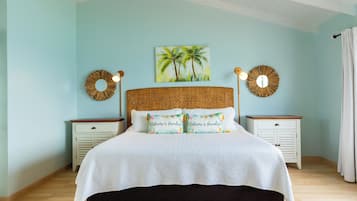 Quarto com cama, duas mesas de cabeceira, pintura de palmeiras e duas arandelas.
