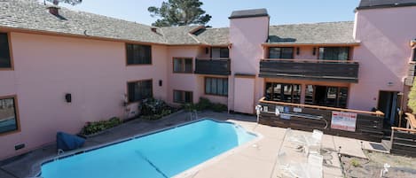 Un área de piscina con una piscina azul cristalina, asientos exteriores y un edificio con balcones.