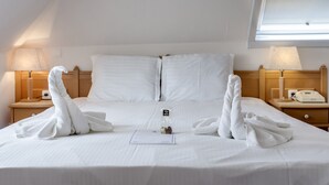 A hotel room with a neatly made bed, two bedside tables with lamps, and a window with a view. - Bryghia Hotel (Bruges)