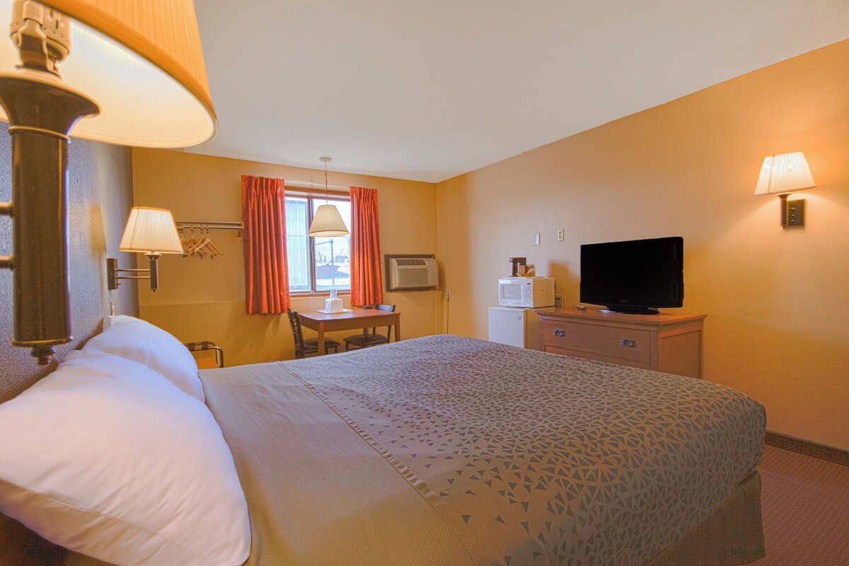 Een hotelkamer met een bed, bureau, televisie en lamp.