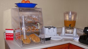 En frukoststation med en genomskinlig behållare för bakverk, en brödrost och en kaffedispenser.