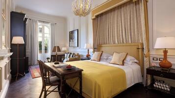 A well-appointed hotel room with a large bed, a dining area, and a chandelier.