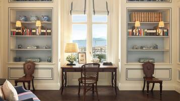 Un bureau avec une chaise, deux fauteuils et des étagères décorées d’objets d’art.