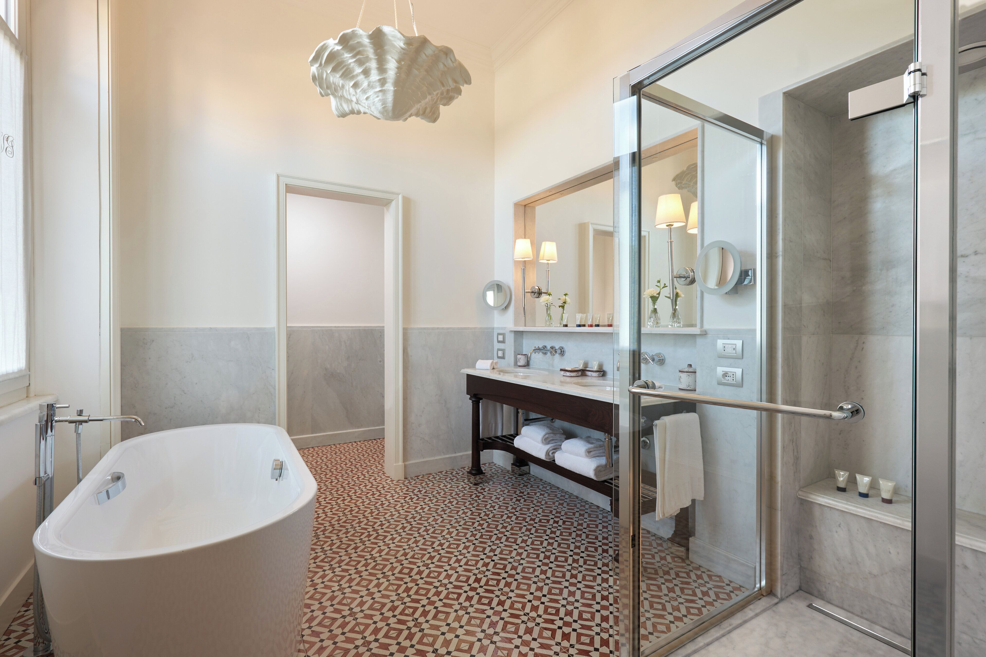 A modern bathroom with a freestanding bathtub, a glass-enclosed shower, and a vanity with a mirror and towel rack.