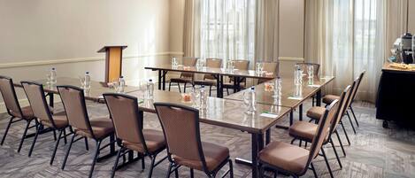 Une salle de conférence avec une longue table, des chaises et un pupitre.