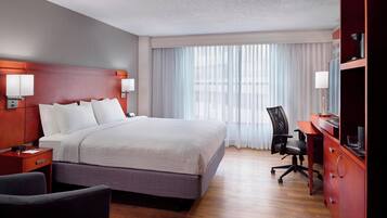 Une chambre d’hôtel avec un grand lit, un bureau, une chaise et un téléviseur.