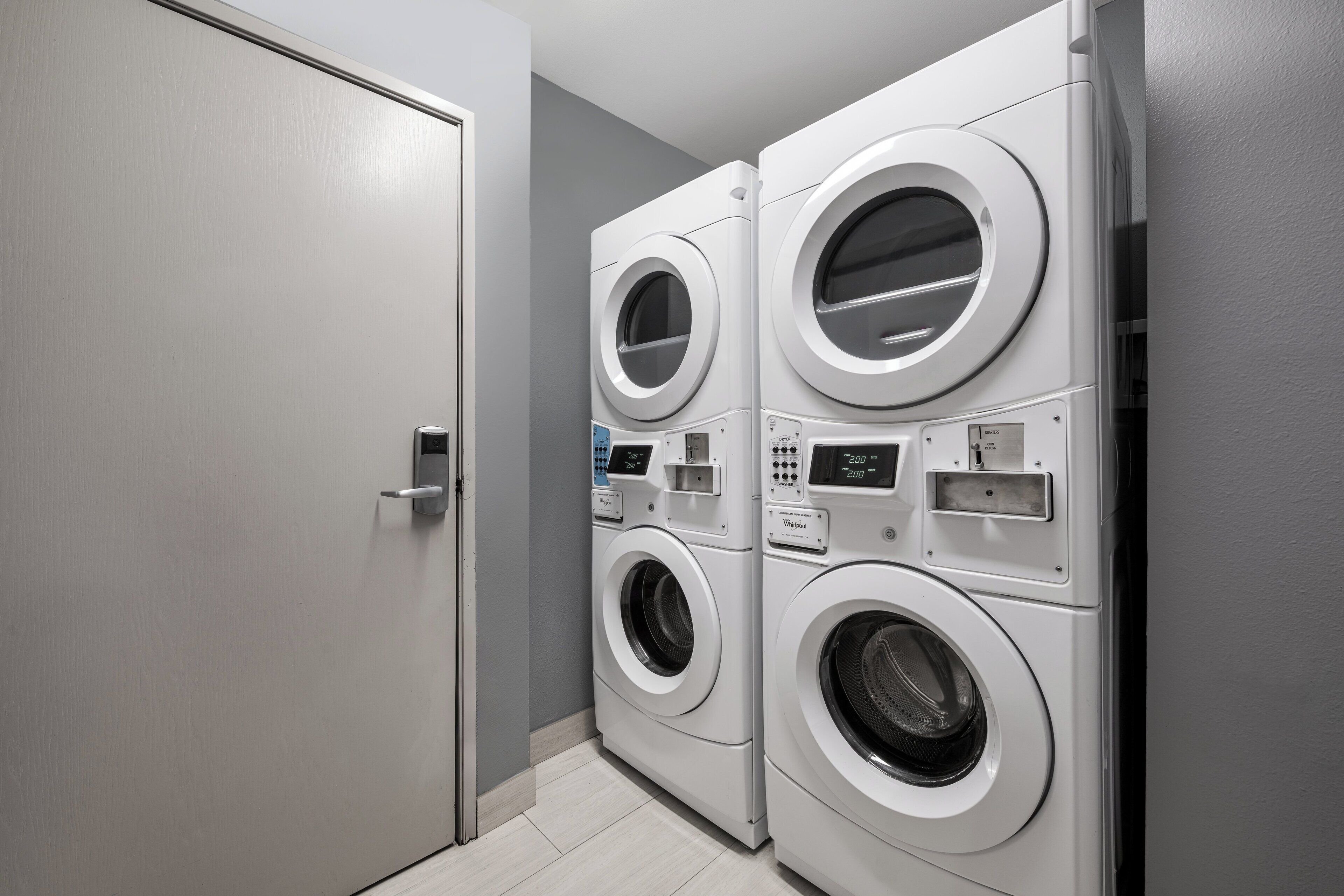 A laundry room with two stacked front-loading washing machines and a closed door.