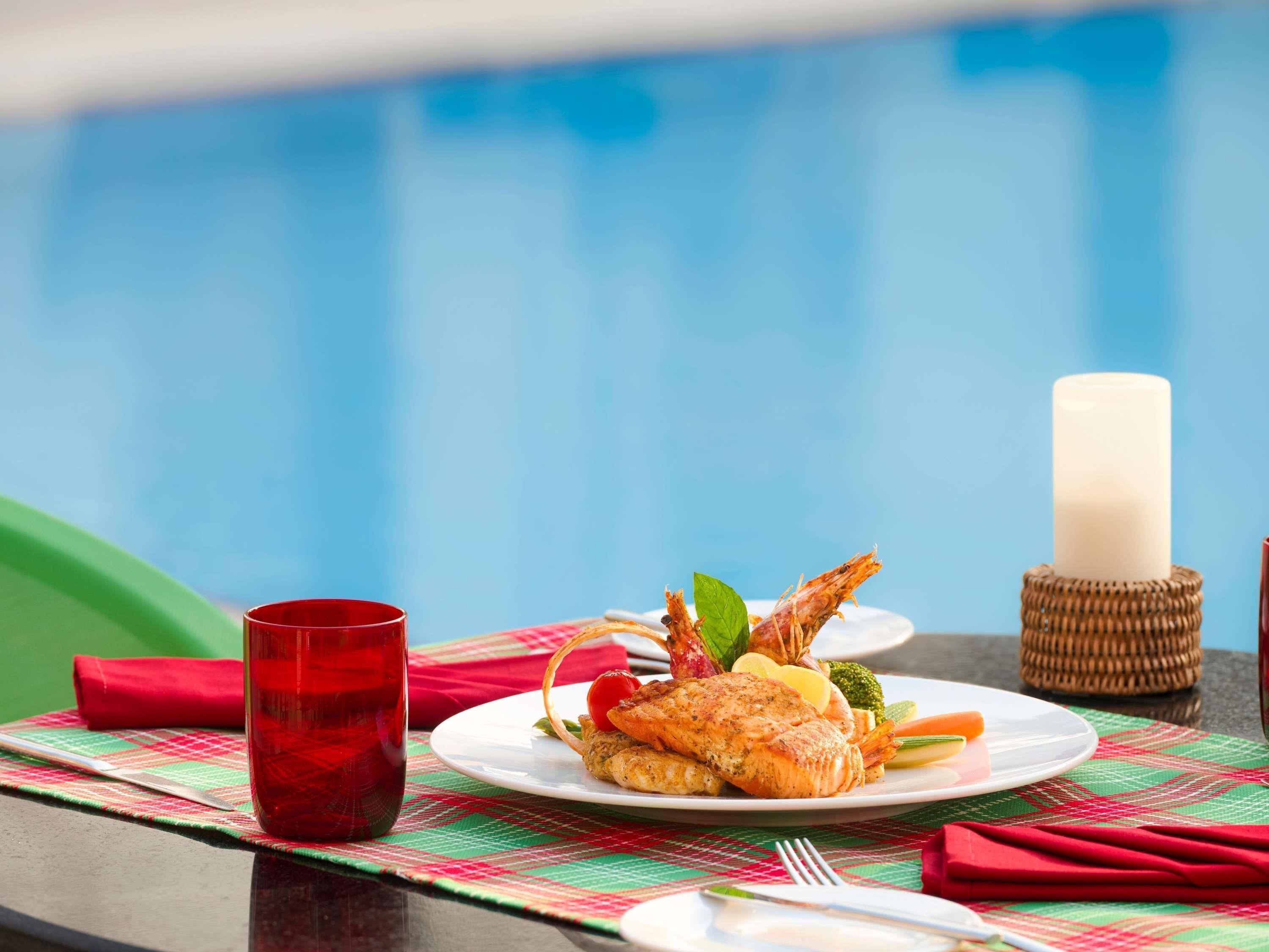 Een eettafel met een bord eten, een rood drankje en een kaars.