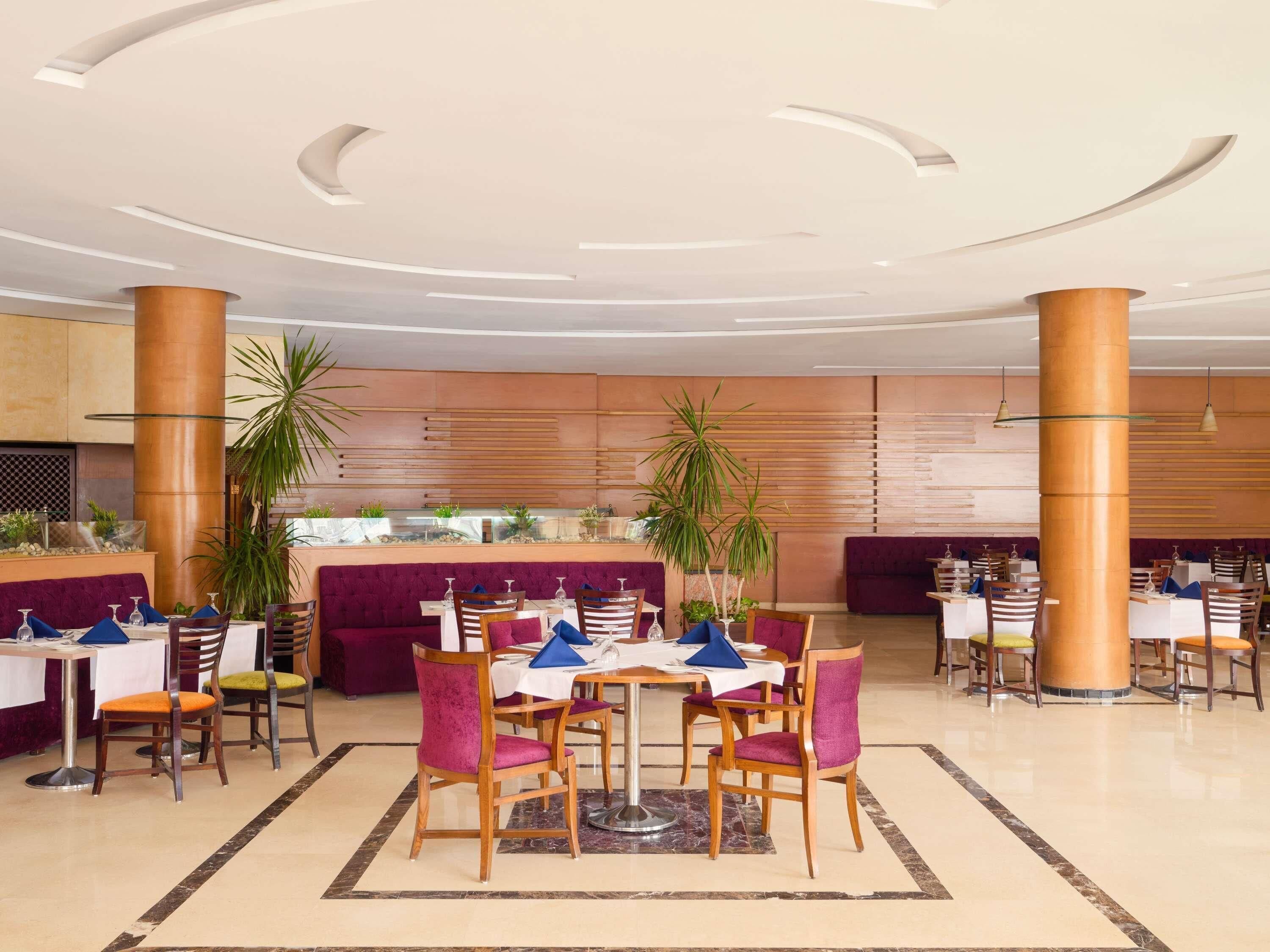 Un espace repas moderne avec des tables rondes, des chaises et un élément décoratif central.