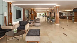 A spacious lobby with seating areas, a reception desk, and a TV screen. - Novotel Cairo Airport (Cairo)
