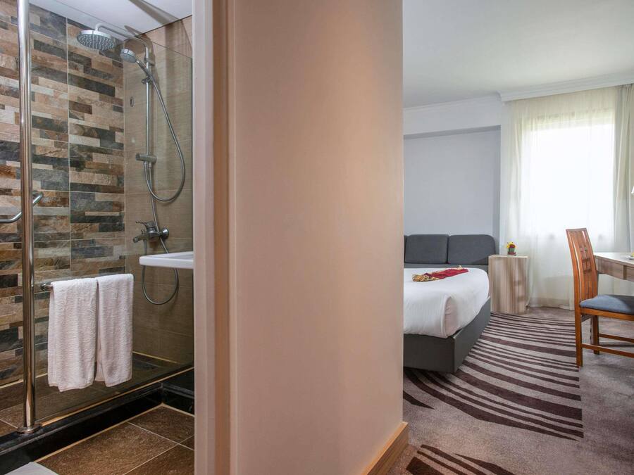 Una habitación de hotel con ducha, cama, escritorio y silla.