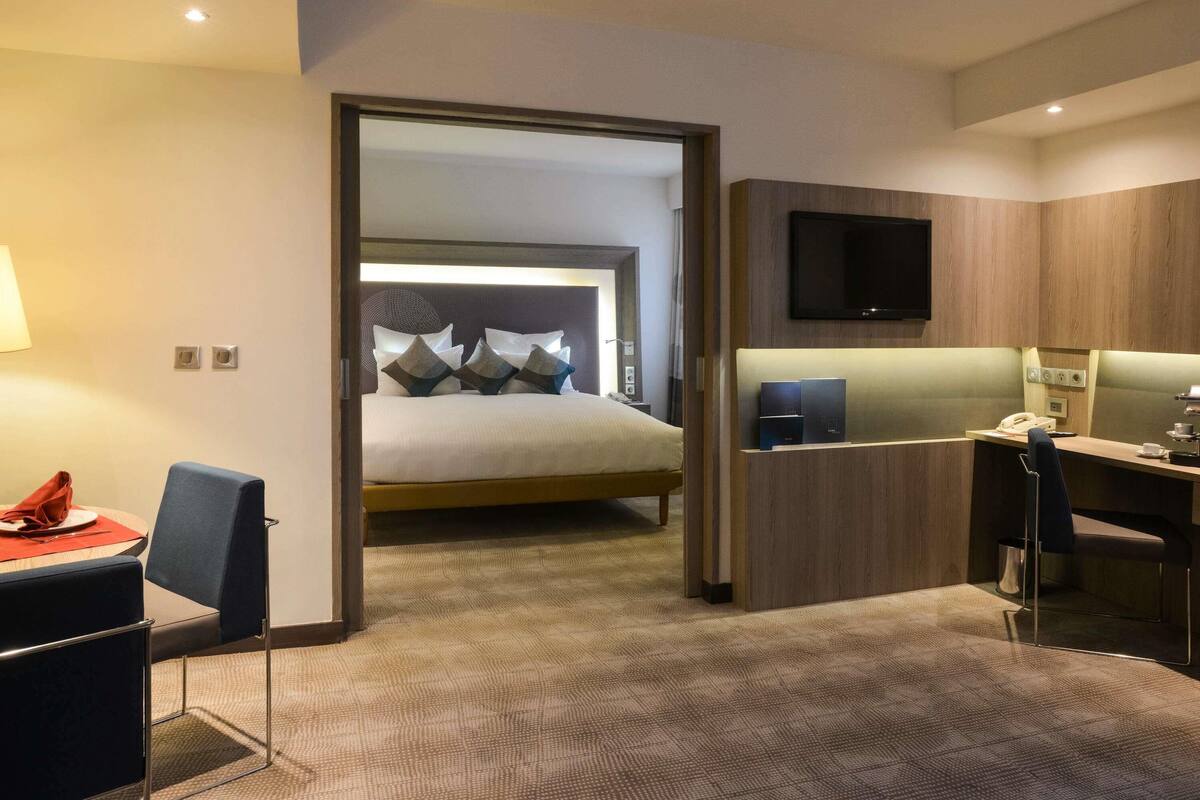 Una habitación de hotel con una cama, un escritorio, una silla, un televisor y una lámpara.