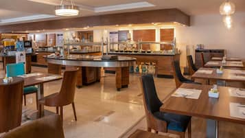 Een modern restaurant in een hotel, met een centrale bar, meerdere eettafels en een buffetgedeelte.