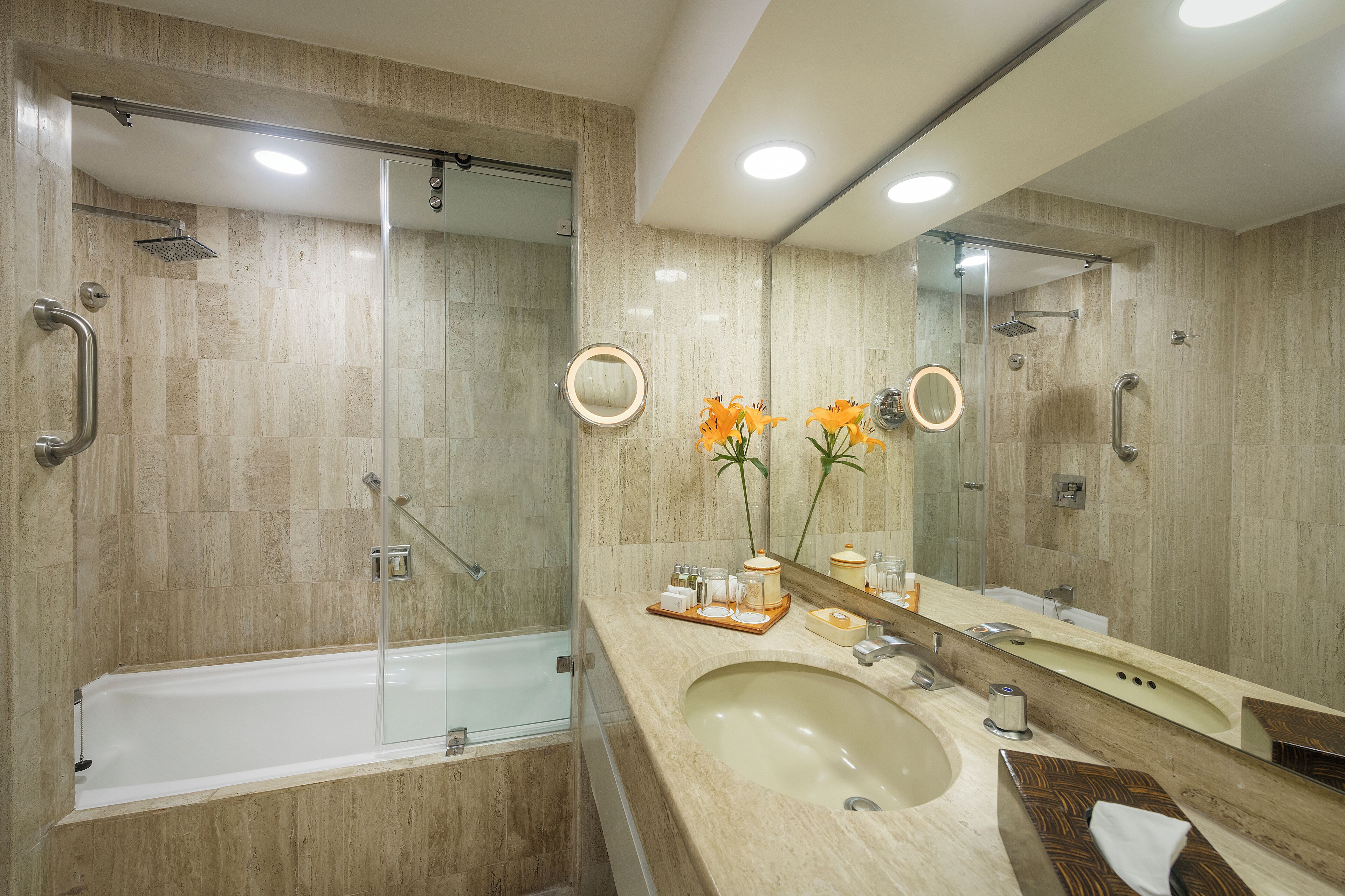 A modern bathroom with a glass-enclosed shower, a large sink, and a vanity mirror.