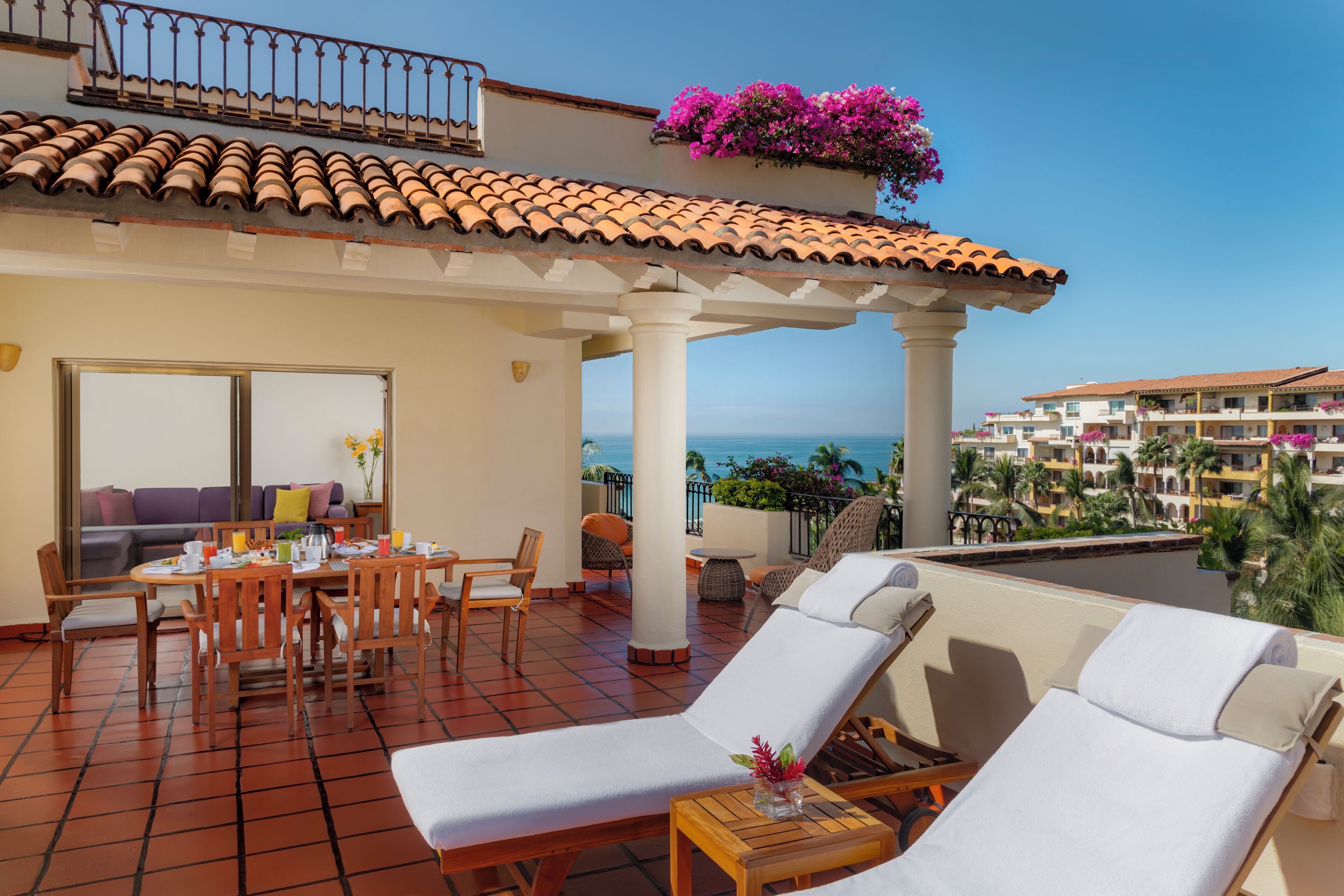 Una terrazza con zona pranzo, poltrone relax e vista sul mare.