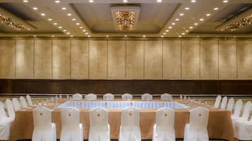 A conference room with a long table, white chairs, and a beige carpet.