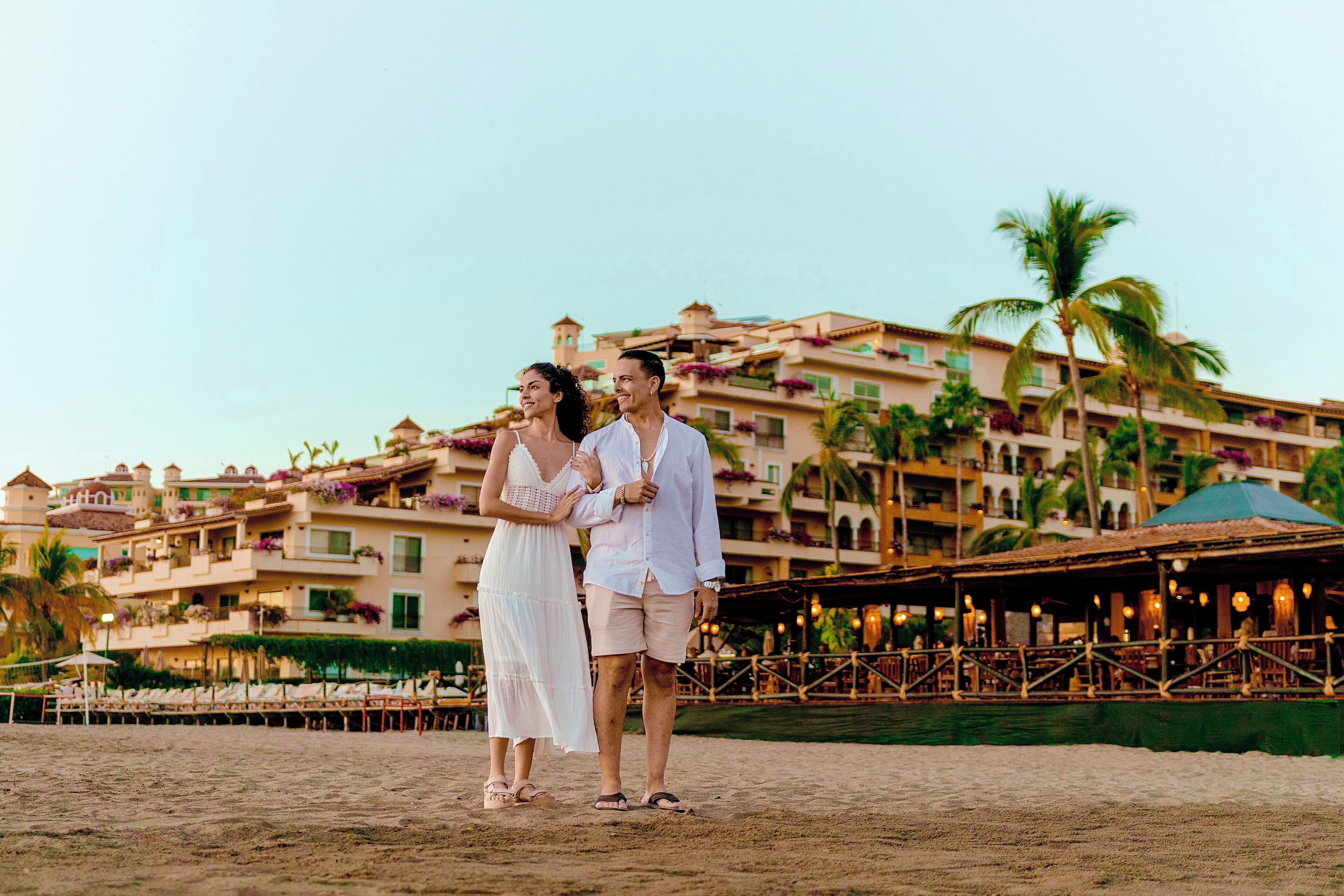 A resort with multiple balconies, palm trees, and outdoor seating areas.