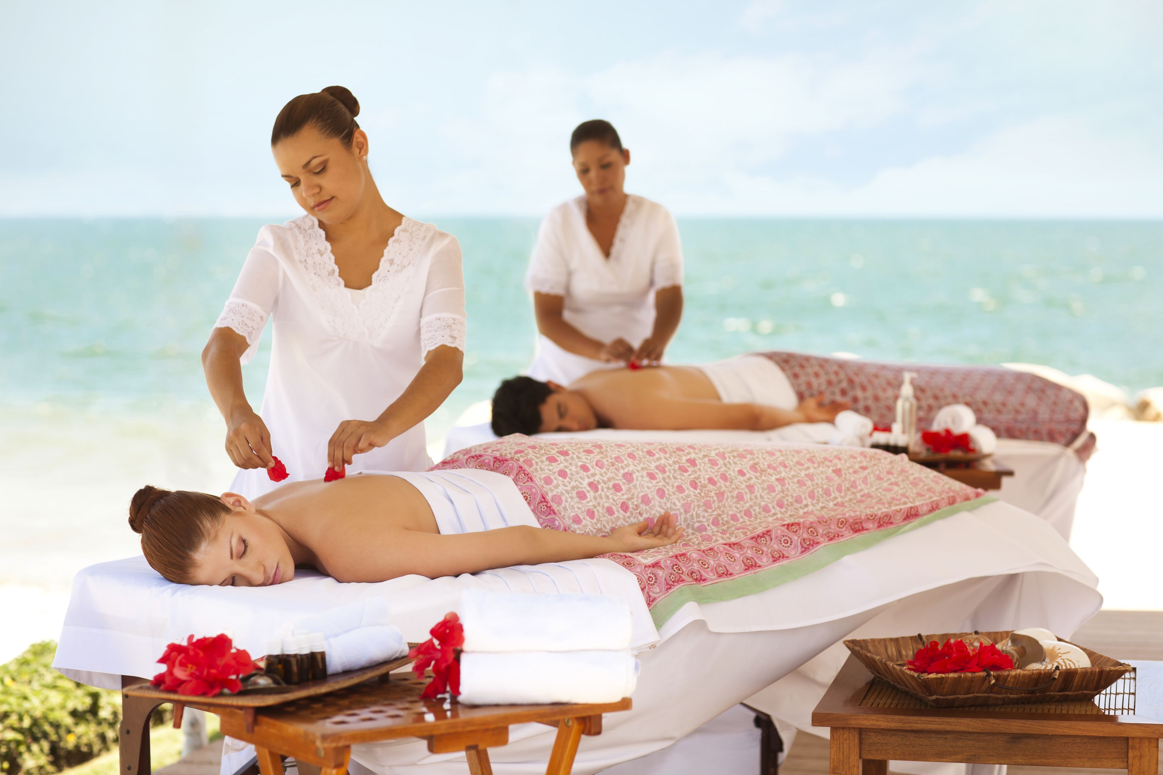 A spa setting with massage tables and a beach view.