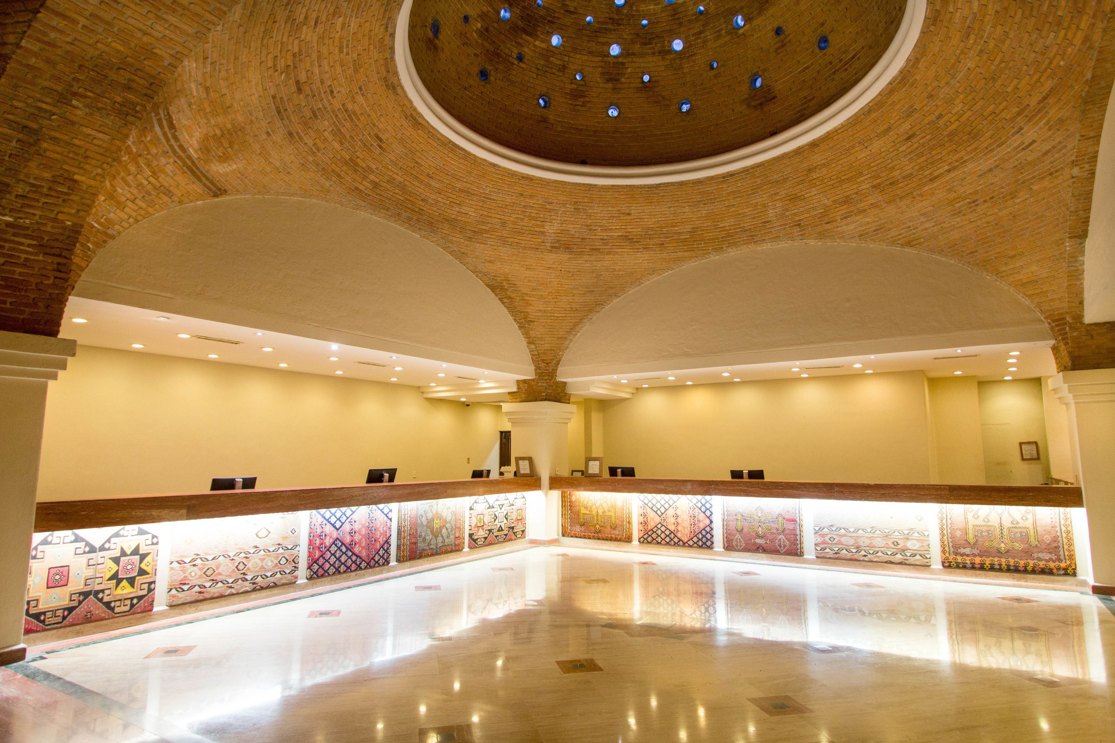 Um hall amplo com teto alto e abobadado e um balcão de recepção extenso.