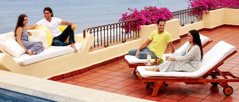 Zona junto a la piscina con sillones de descanso, jacuzzi y vista al mar.