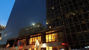 A modern high-rise hotel with a glass facade, a prominent entrance with a flag, and a Marriott logo.