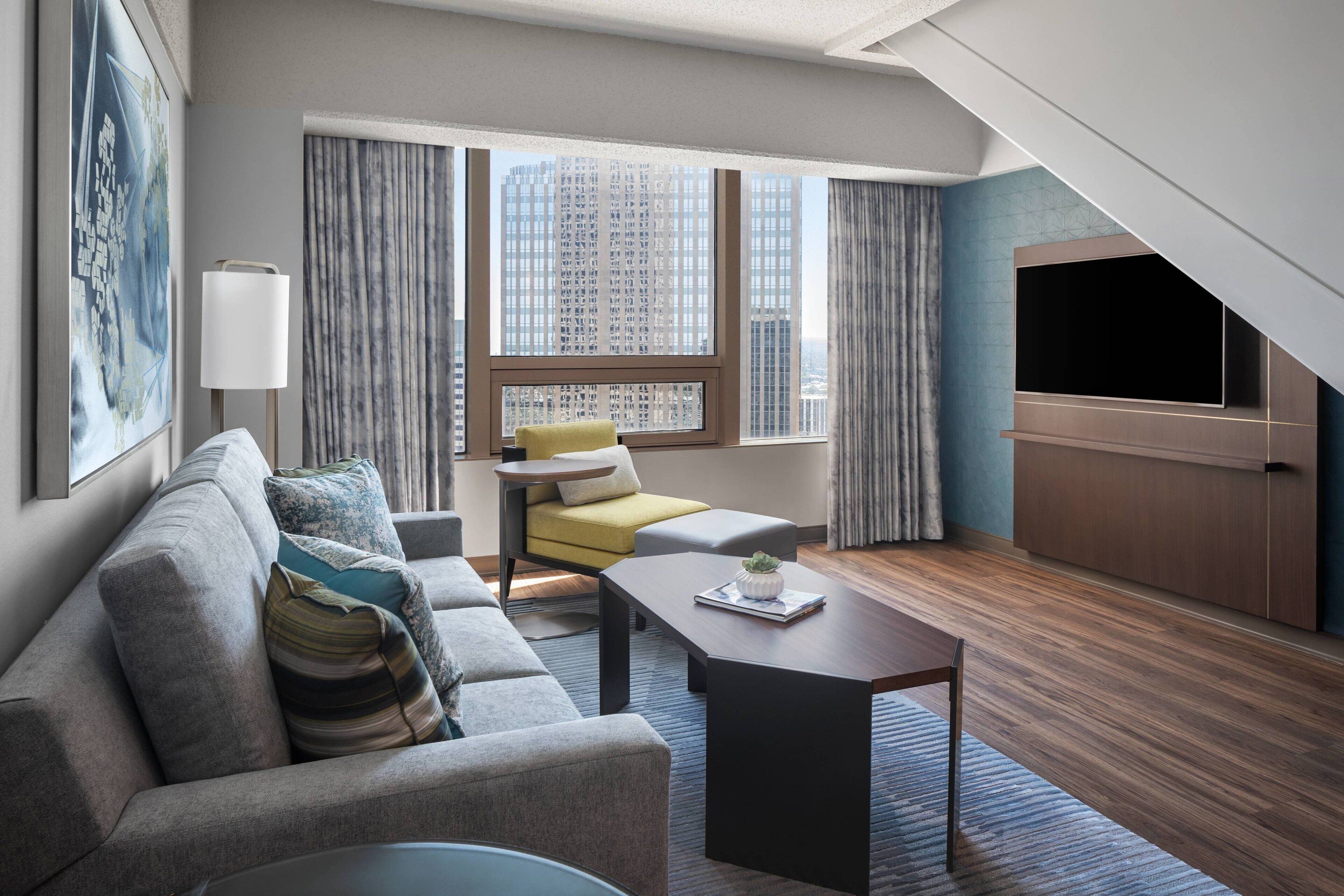 Et moderne hotelværelse med sofa, lænestol og fladskærms-tv.