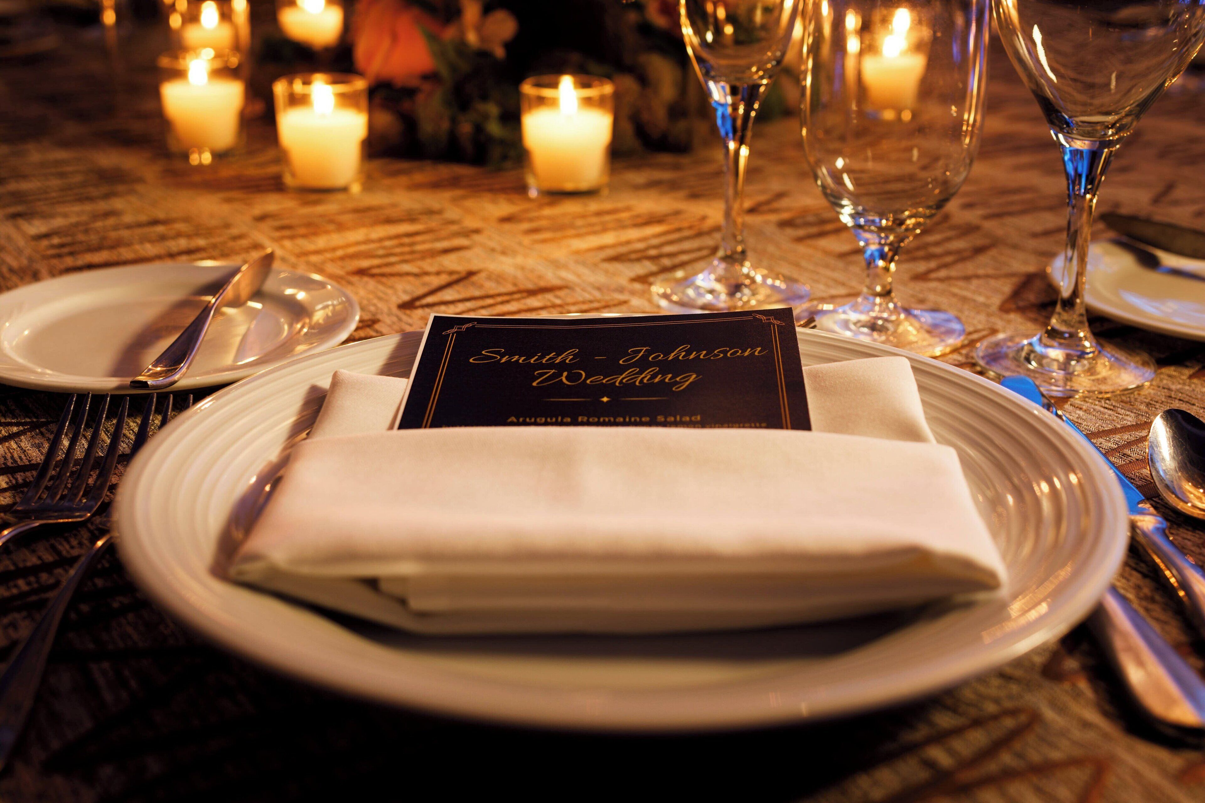 A table set for a wedding with candles, plates, cutlery, and a menu card.