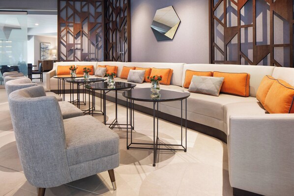 Una sala moderna con un conjunto de sofás, dos mesas redondas y un sillón gris.