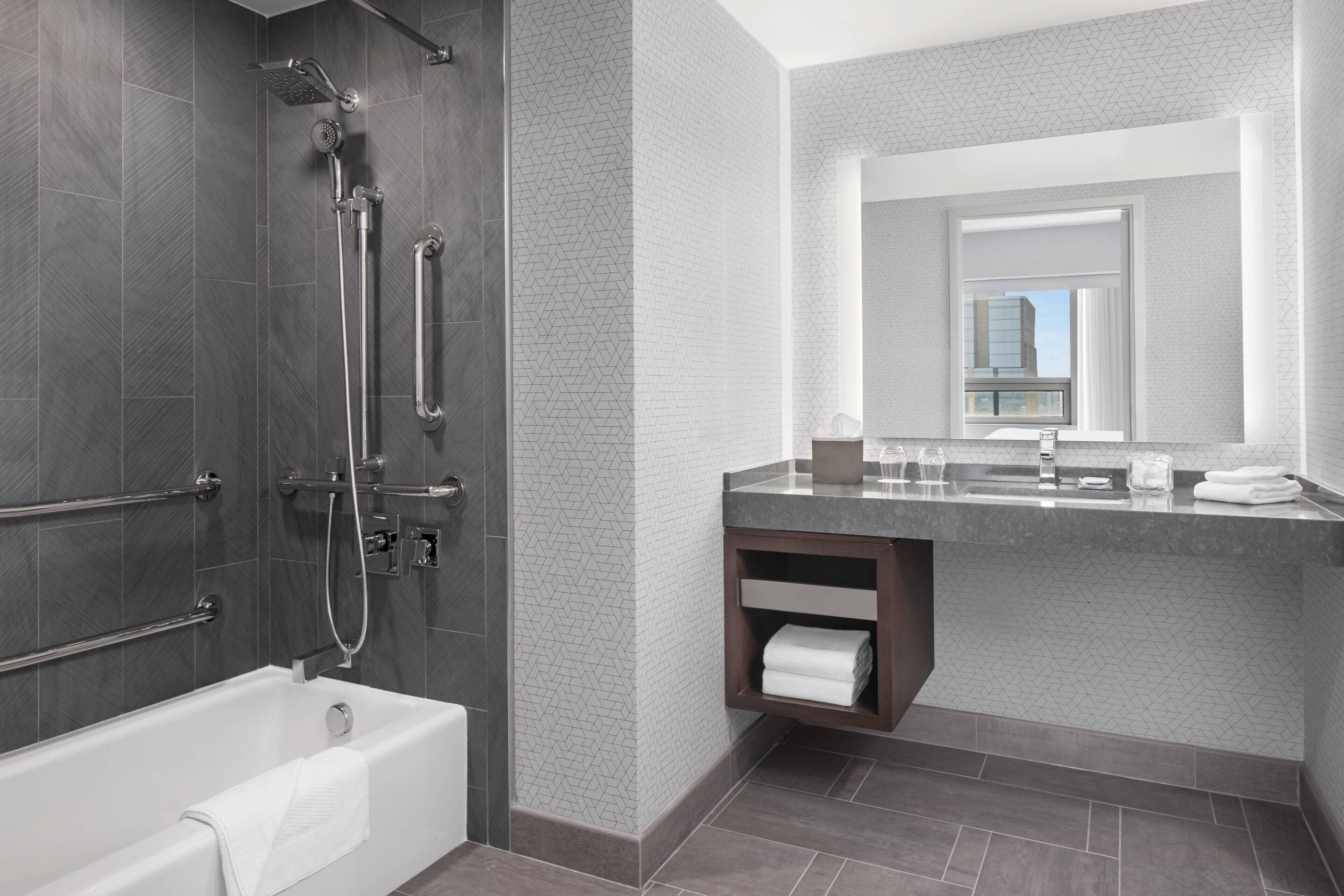 A modern bathroom with a bathtub, shower, and vanity with a mirror.