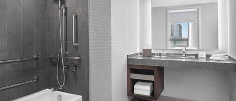 A modern bathroom with a bathtub, shower, and vanity with a mirror.