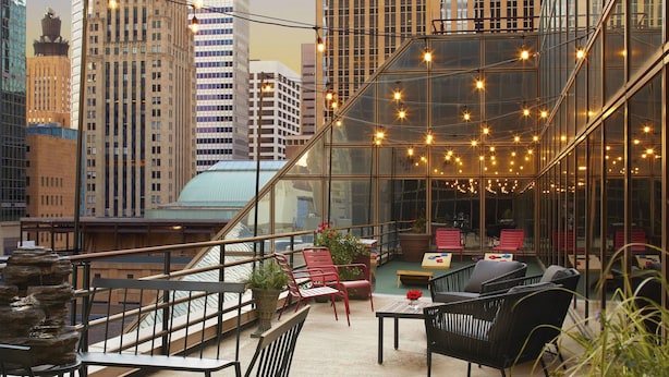 A rooftop terrace with outdoor seating, a glass wall, and city views.