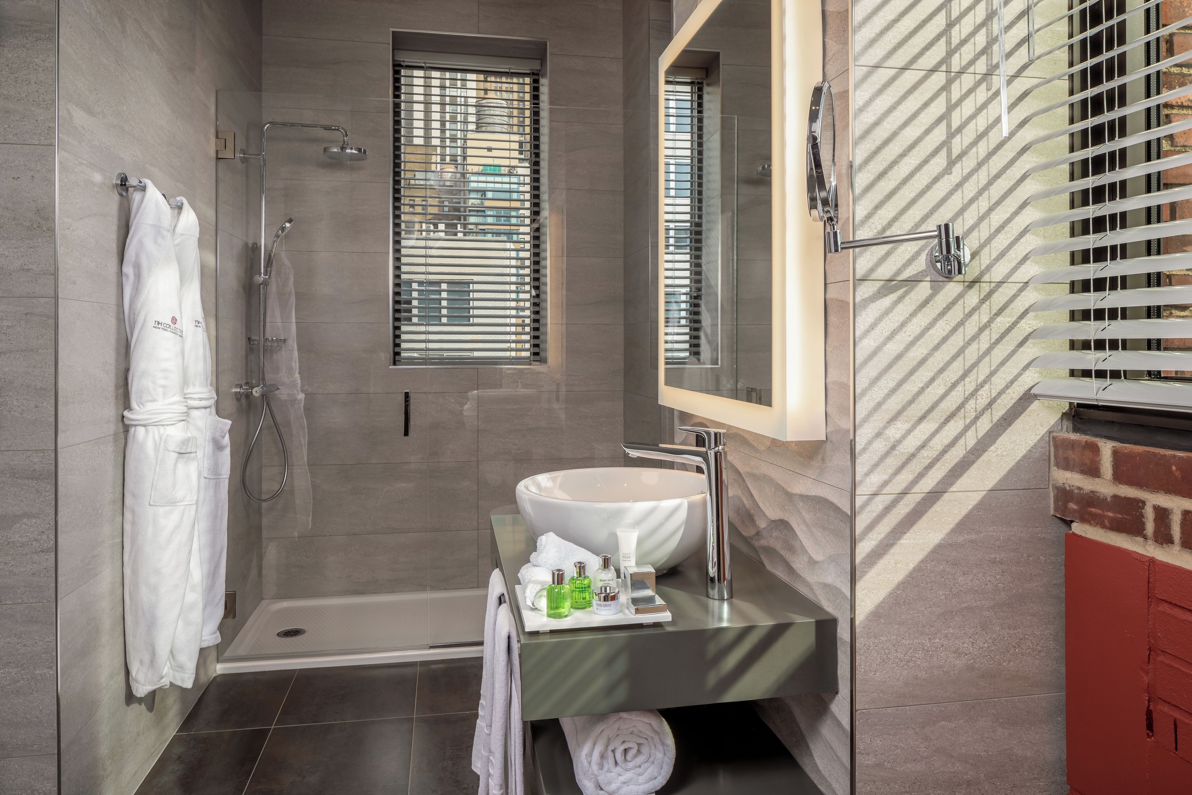 A modern bathroom with a walk-in shower, a large sink, and a mirror above it.