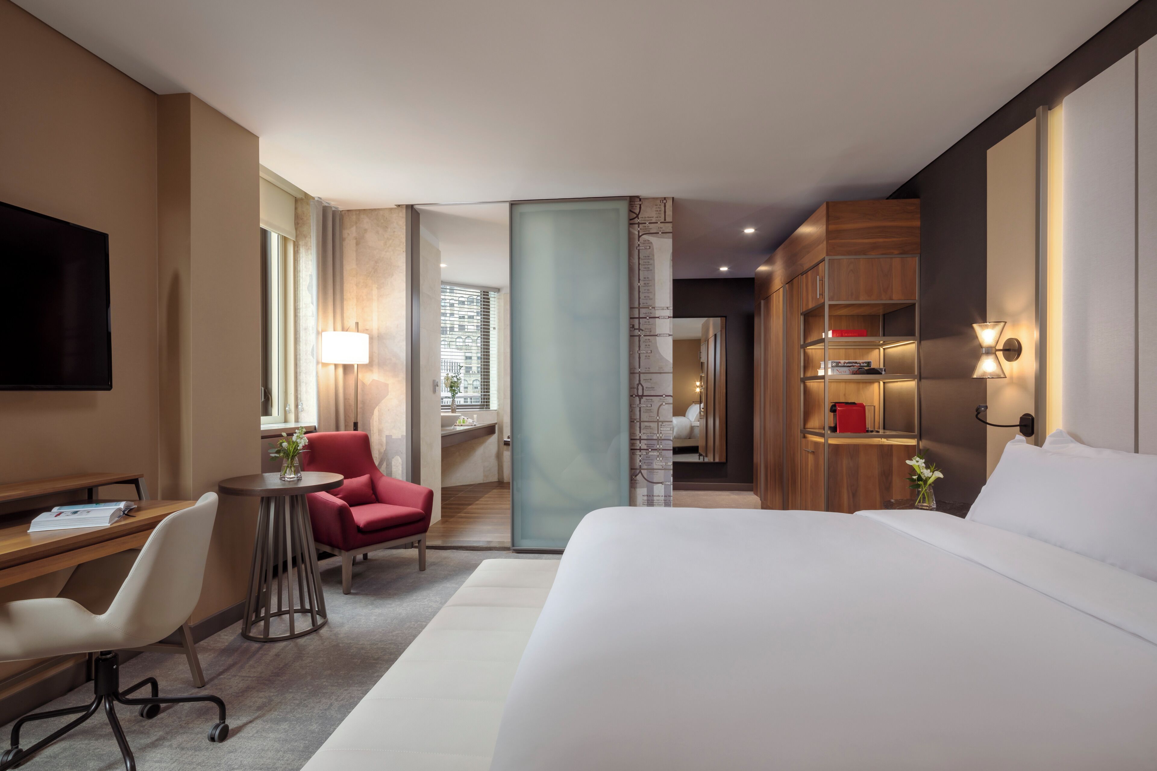 Une chambre d’hôtel équipée d’un lit, d’un bureau, d’une chaise, d’une lampe et offrant une vue sur la ville.