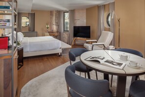 A hotel room with a bed, a desk, a TV, a chair, a table, and a bookshelf. - NH Collection New York Madison Avenue (New York)