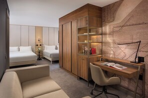 Una habitación de hotel con una cama, un escritorio con silla, un sofá y un mapa grande en la pared.
