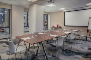 A conference room with a long table, chairs, a projector, and a screen. - NH Collection New York Madison Avenue (New York)