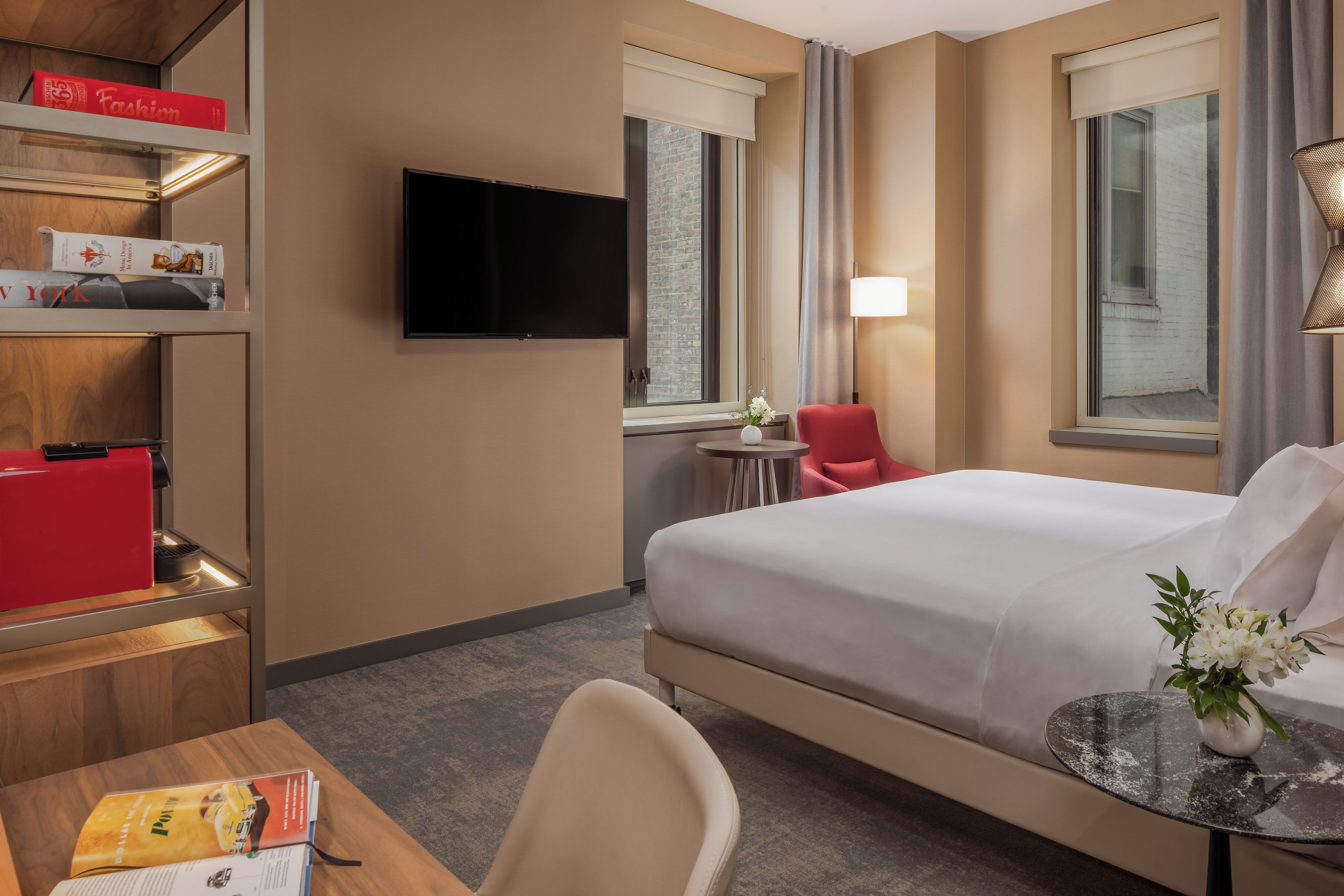 A hotel room with a bed, a desk, a chair, a TV, and a window with curtains.