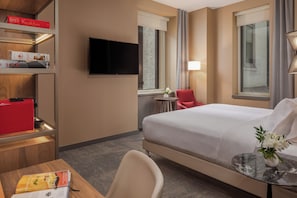 A hotel room with a bed, a desk, a chair, a TV, and a window with curtains. - NH Collection New York Madison Avenue (New York)