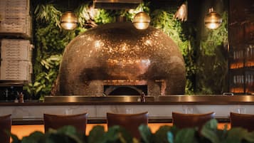 L’intérieur d’un restaurant avec un four en briques, des luminaires suspendus et un panneau affichant le menu.