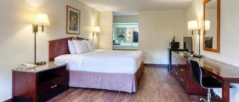 Ein Hotelzimmer mit einem Bett, Nachttischlampen, einem Schreibtisch mit Stuhl, einem Spiegel und einer Kommode.