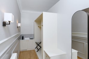 A modern, well-lit room with a white wardrobe, a small table with a kettle, and a radiator.