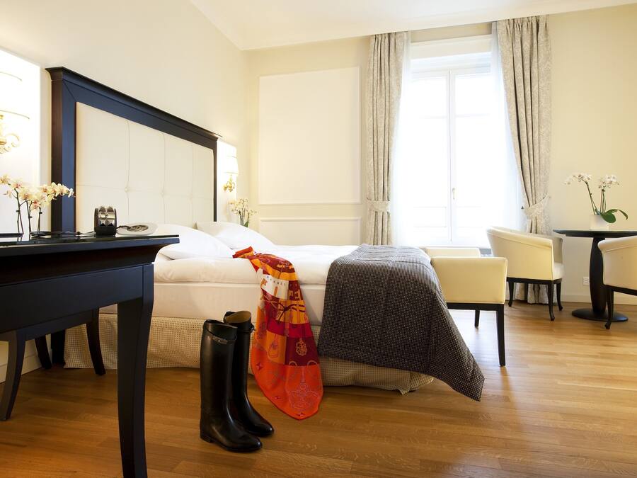 Habitació d'hotel amb llit, escriptori, cadira i taula amb un ram de flors.