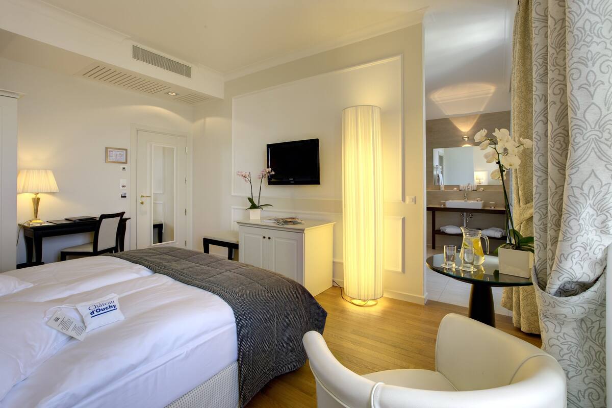 A hotel room with a bed, desk, chair, TV, lamp, and bathroom.