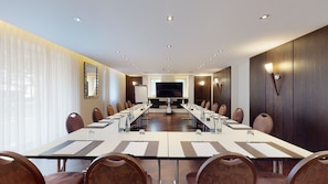 A conference room with a long table, chairs, a large screen, and a whiteboard.