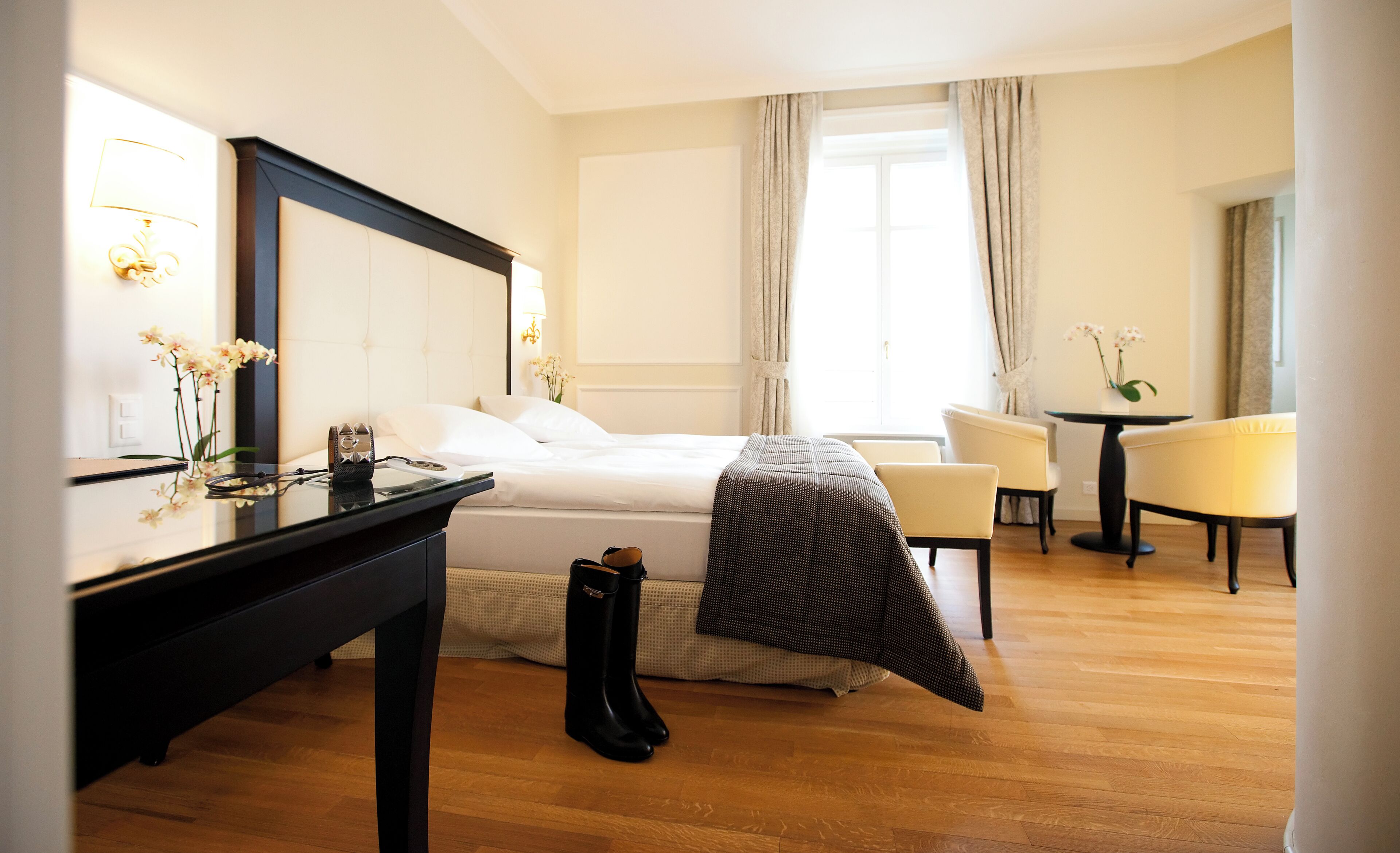 A hotel room with a bed, a desk, a chair, and a small table.