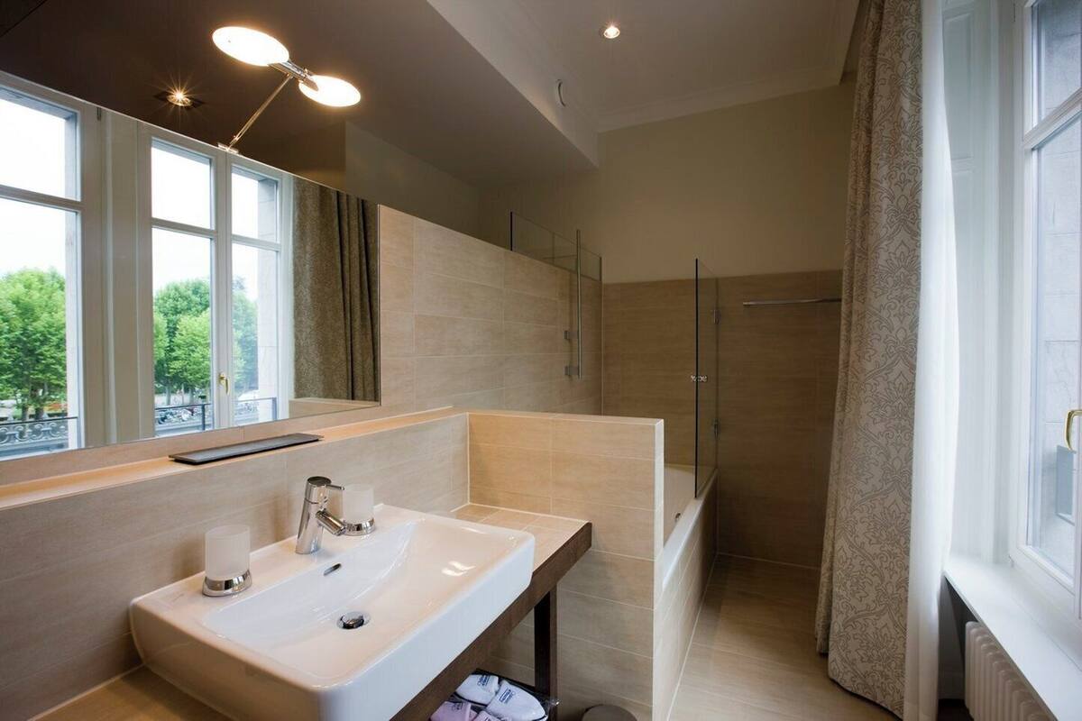 A modern bathroom with a large mirror, a sink, and a shower area.