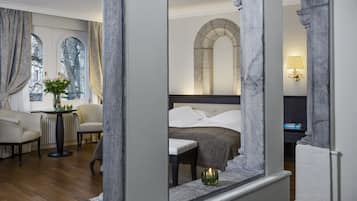 A hotel room with a bed, a chair, a table, and a window with curtains.