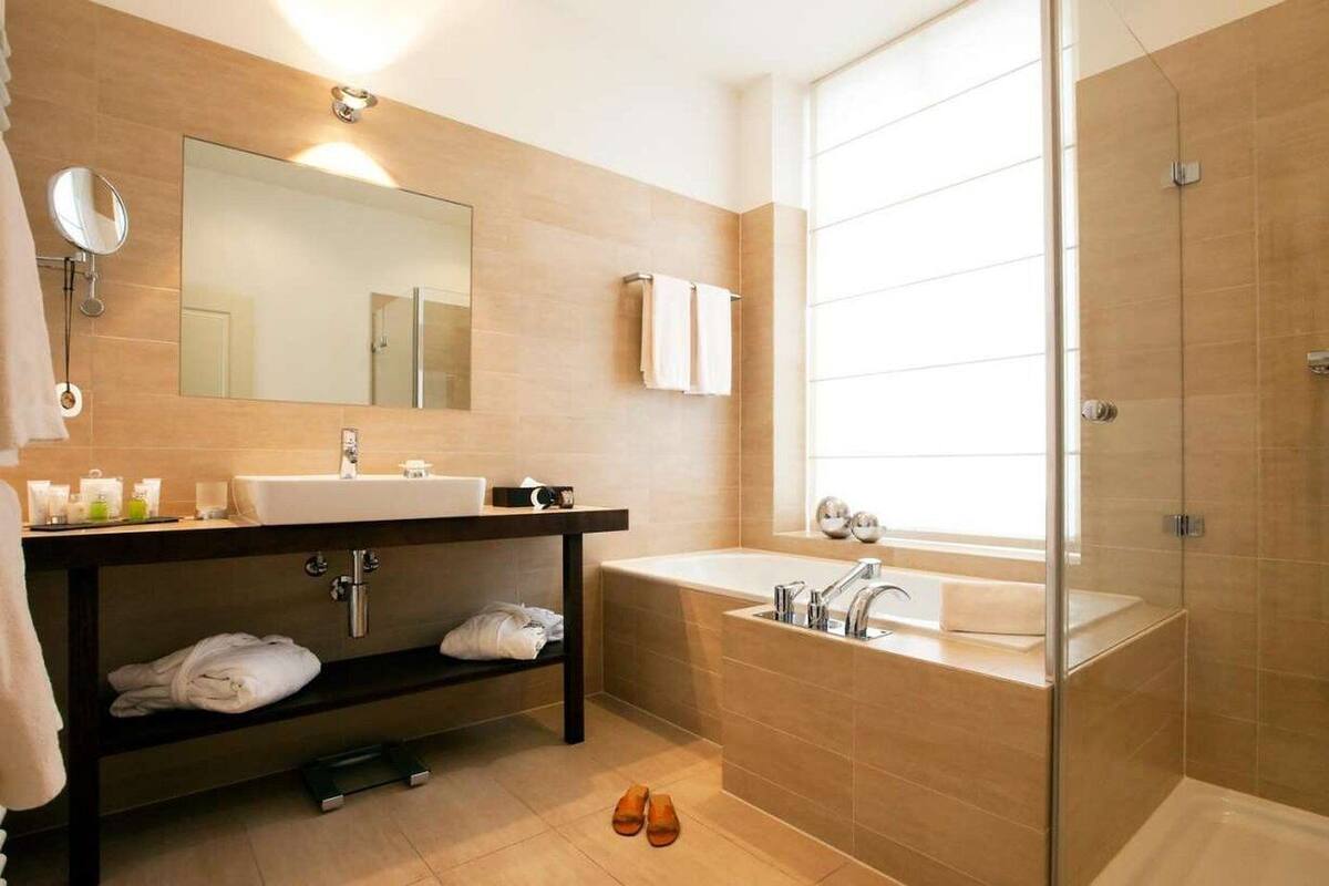 A modern bathroom with a large mirror, a sink, a bathtub, and a shower.